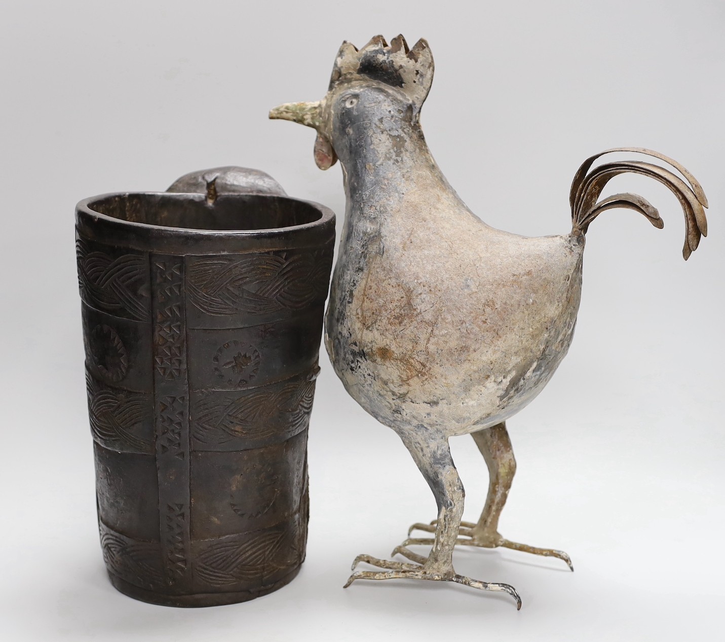 An 18th century Scandinavian carved wood tankard and a 19th century painted tin plated iron model of a cockerel, 36.5cm high.